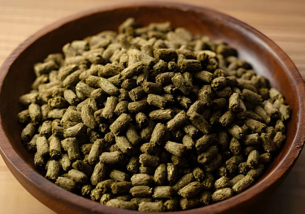 Close-up of alfalfa meal pellets in a wooden bowl, showing one of the plant-based organic fertilizer types used in gardens.