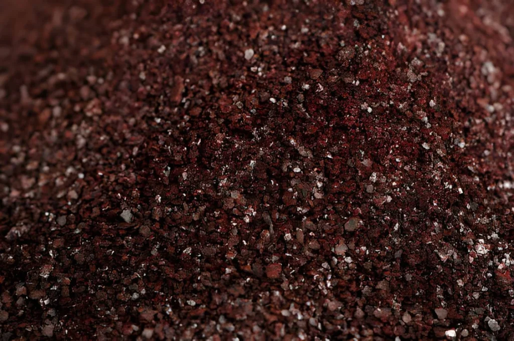 Close-up of dark red blood meal, showing one of the nitrogen-rich organic fertilizer types used to support leafy plant growth.